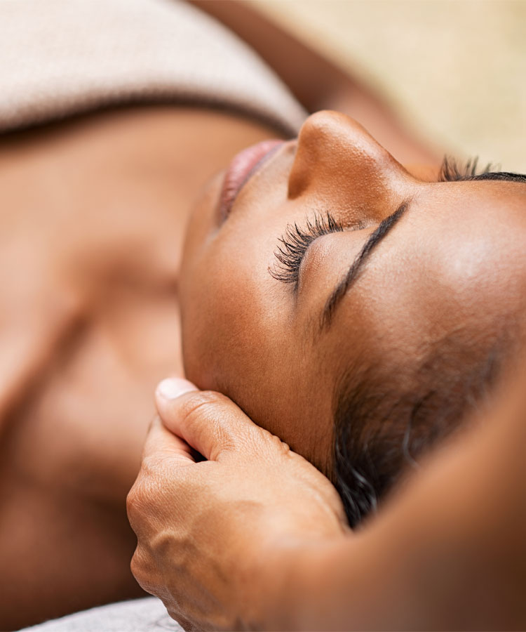 close up of a woman receiving a facial massage from a therapist
