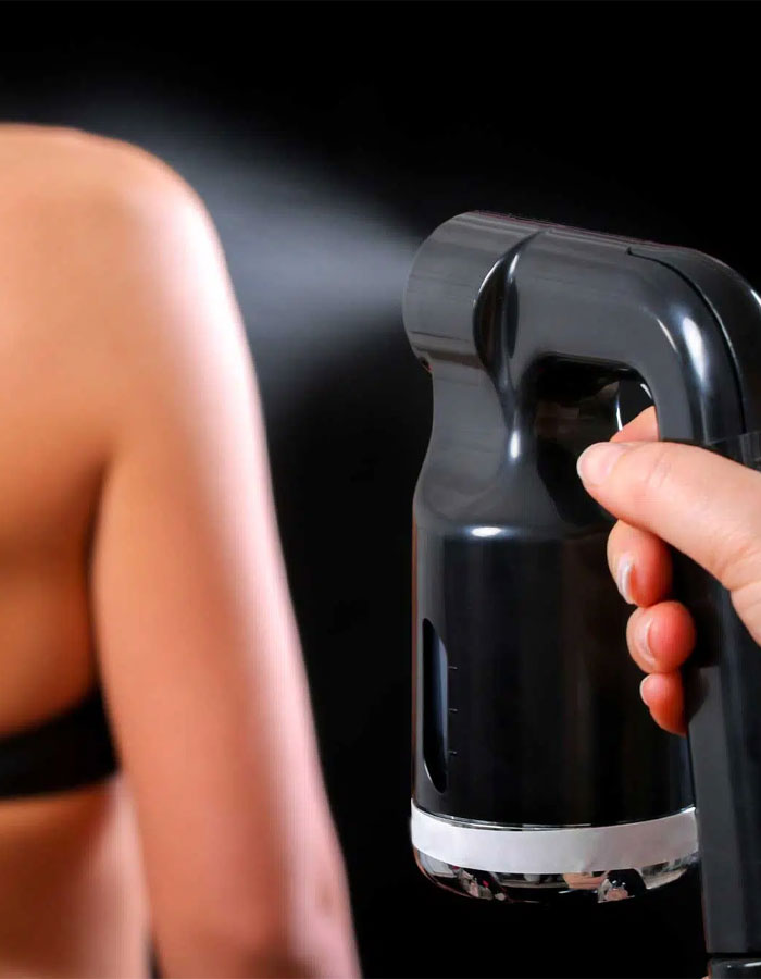 nuessence spa team member spray tanning a client