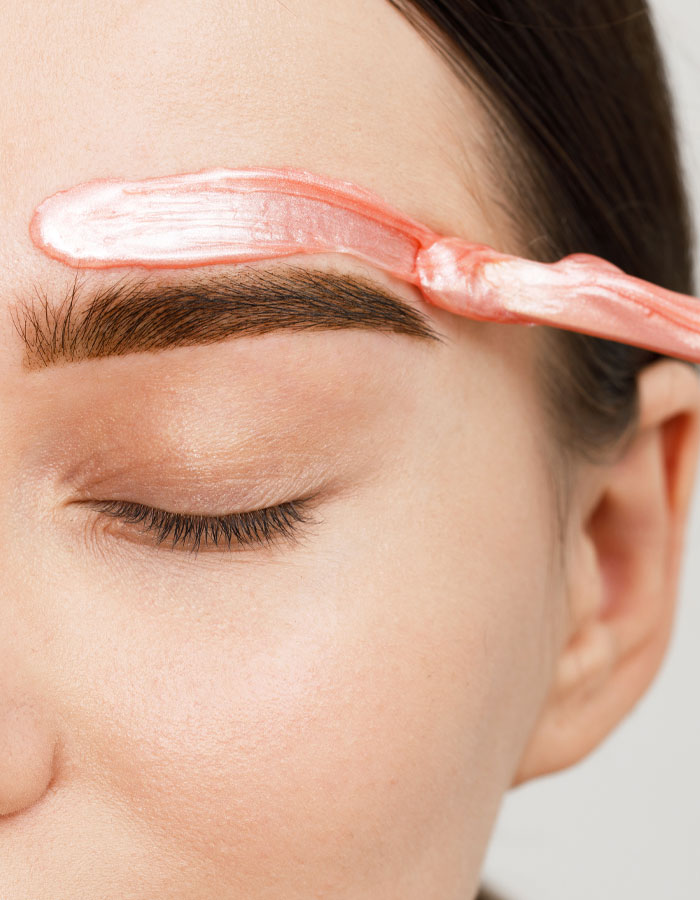 woman applying wax above eyebrow for waxing treatment